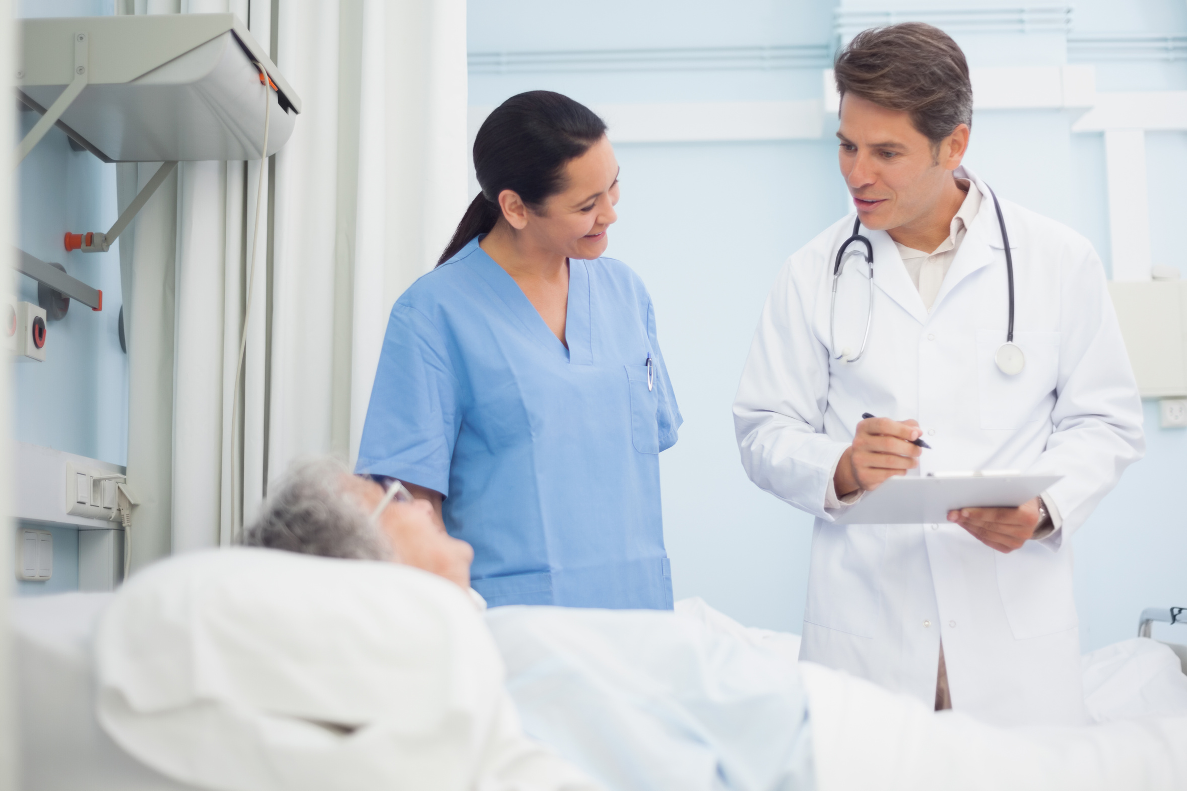 Doctor and nurse talking to a patient in hospital ward