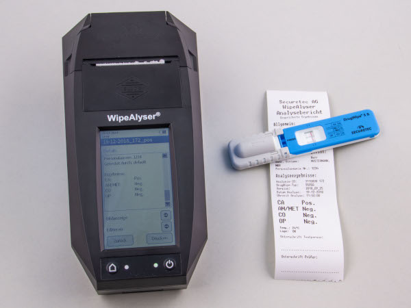 Drogenschnelltest DrugWipe liegt neben Analysegerät WipeAlyser samt einem Ausdruck des Testergebnisses