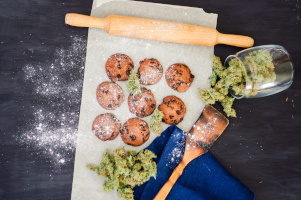 Kekse mit Cannabis neben getrocknetem Cannabis und einem Nudelholz
