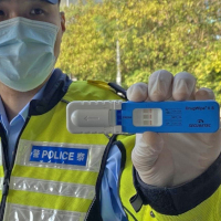 Polizist in Hongkong hält Drogenschnelltest DrugWipe hoch