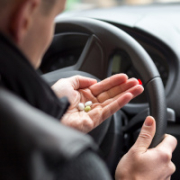Mann am Steuer hält Tabletten in der Hand