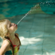 Kleines Kind spuckt im hohen Bogen Wasser ins Schwimmbecken