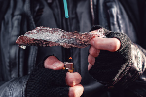 Drogensüchtiger erhitzt Heroin auf Aluminium und atmet den Dampf mit Hilfe eines Strohhalms ein