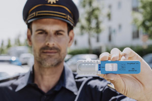 Ein Polizist hält den blau-weißen Drogenschnelltest DrugWipe vor die Kamera