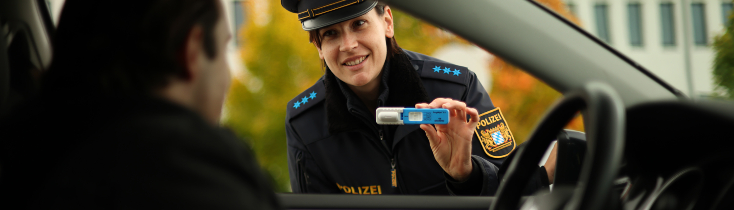dw-s-3-1 Polizei die einen Drogentest in der Hand hält vor einem Autofenster