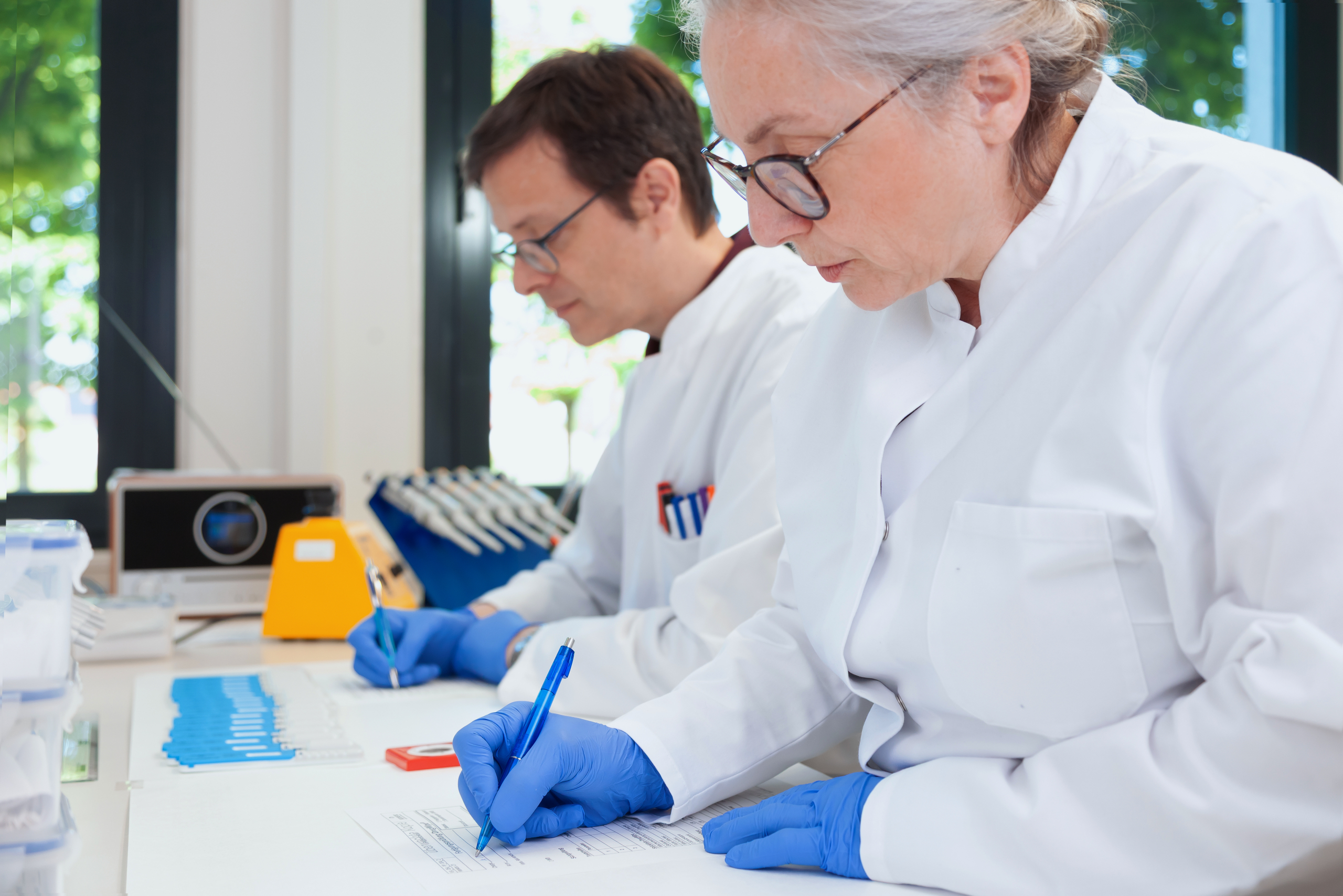 Mehrere DrugWipe Tests nebeneinander und zwei Mitarbeiter, die auf Zetteln das Testergebnis festhalten