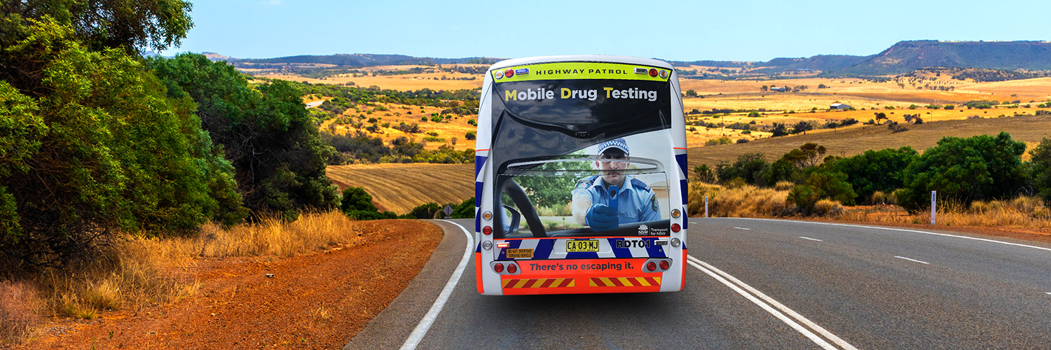 Australische Landschaft mit Bus der Highway Patrol und Aufschrift Mobile Drug Testing