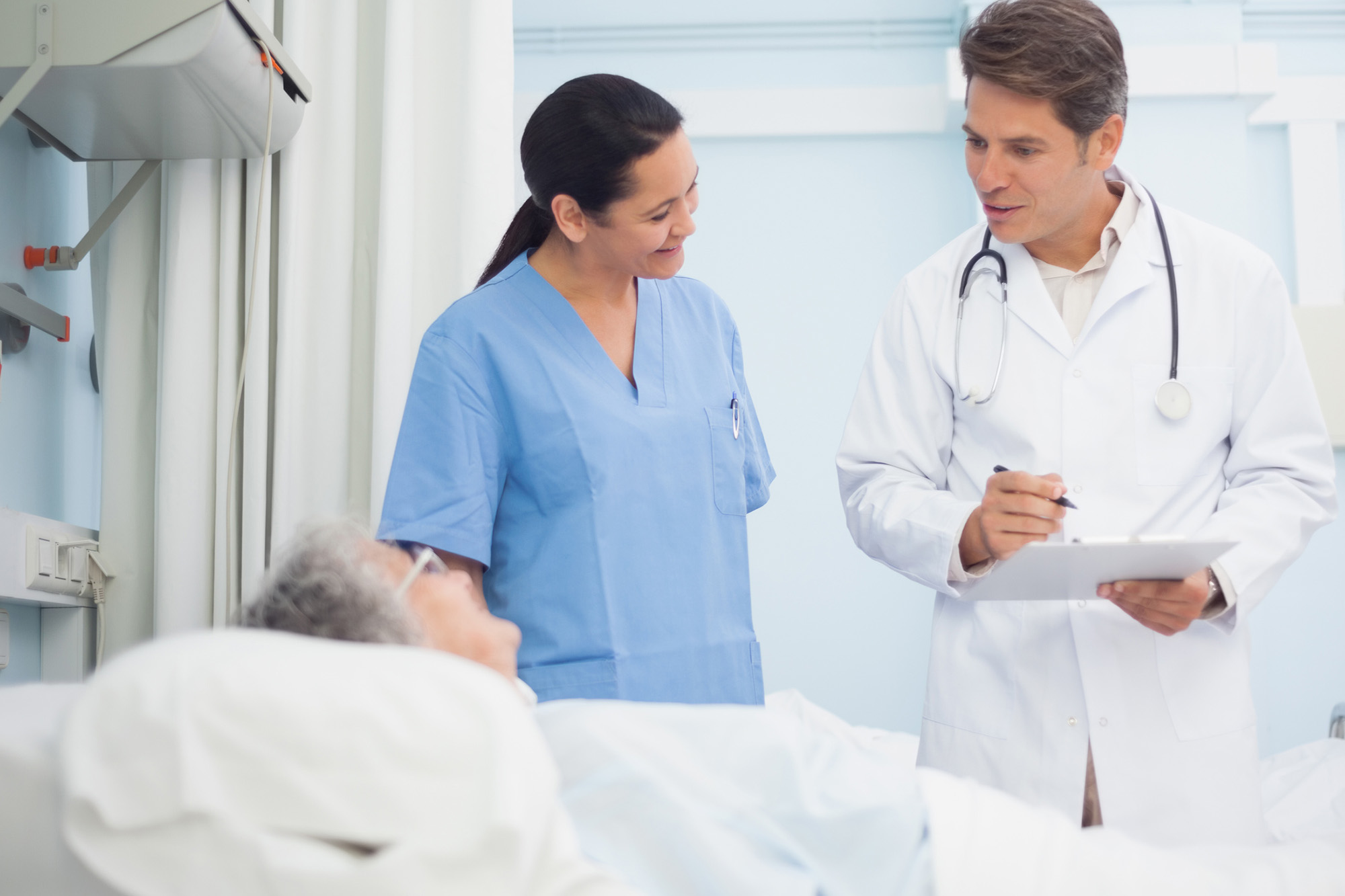 Doctor and nurse talking to a patient in hospital ward Doctor and nurse talking to a patient in hospital ward