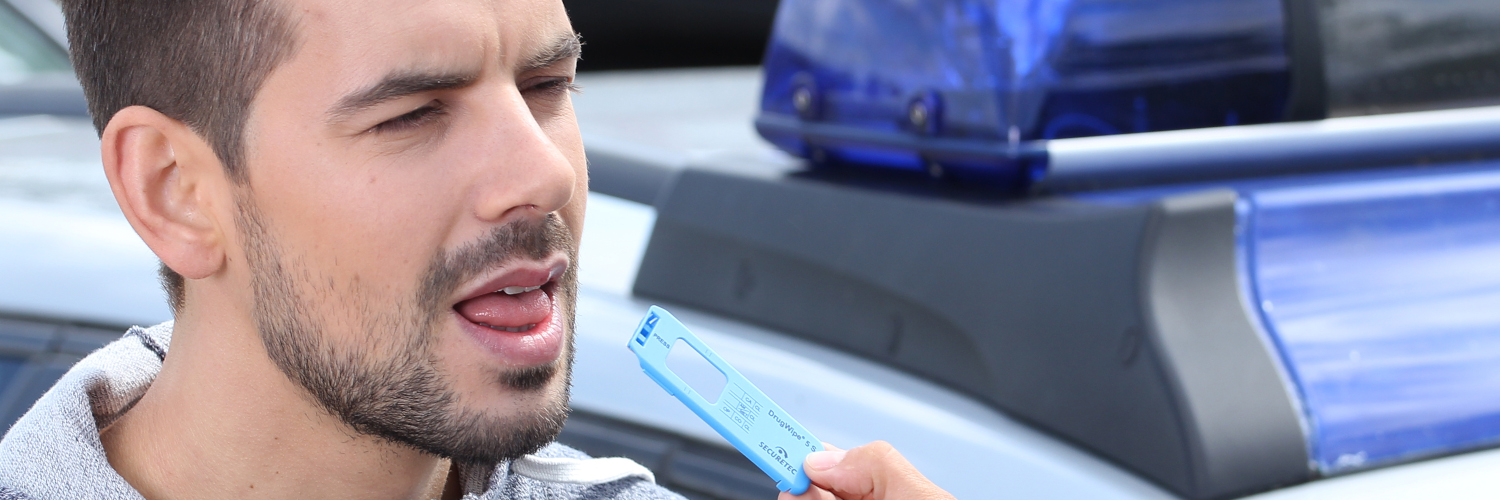 Einem Mann wird bei einer Verkehrskontrolle mit dem Drogenschnelltest DrugWipe 5S Speichel von der Zunge entnommen.
